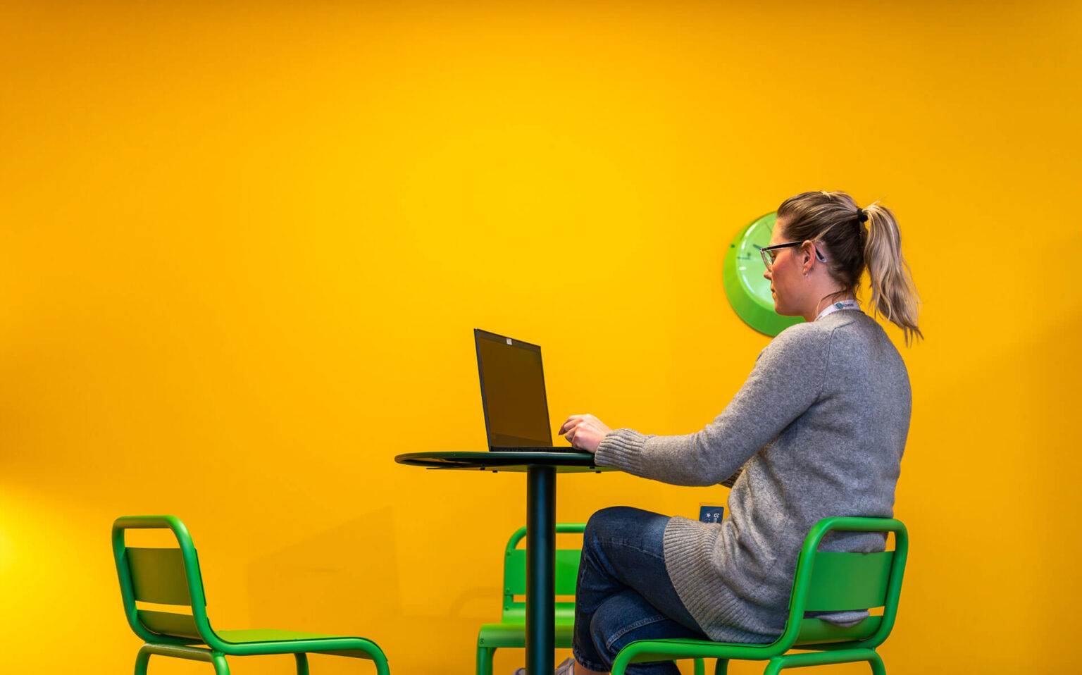 mujer-trabajando-con-portatil-sentada-en-un-tabureta-con-pardes-amarillas-isspaces-insur